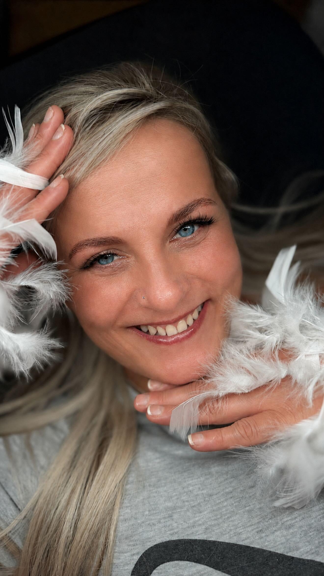 Lachende klant met witte veren boa, met nieuwe wimpers en wenkbrauwen
