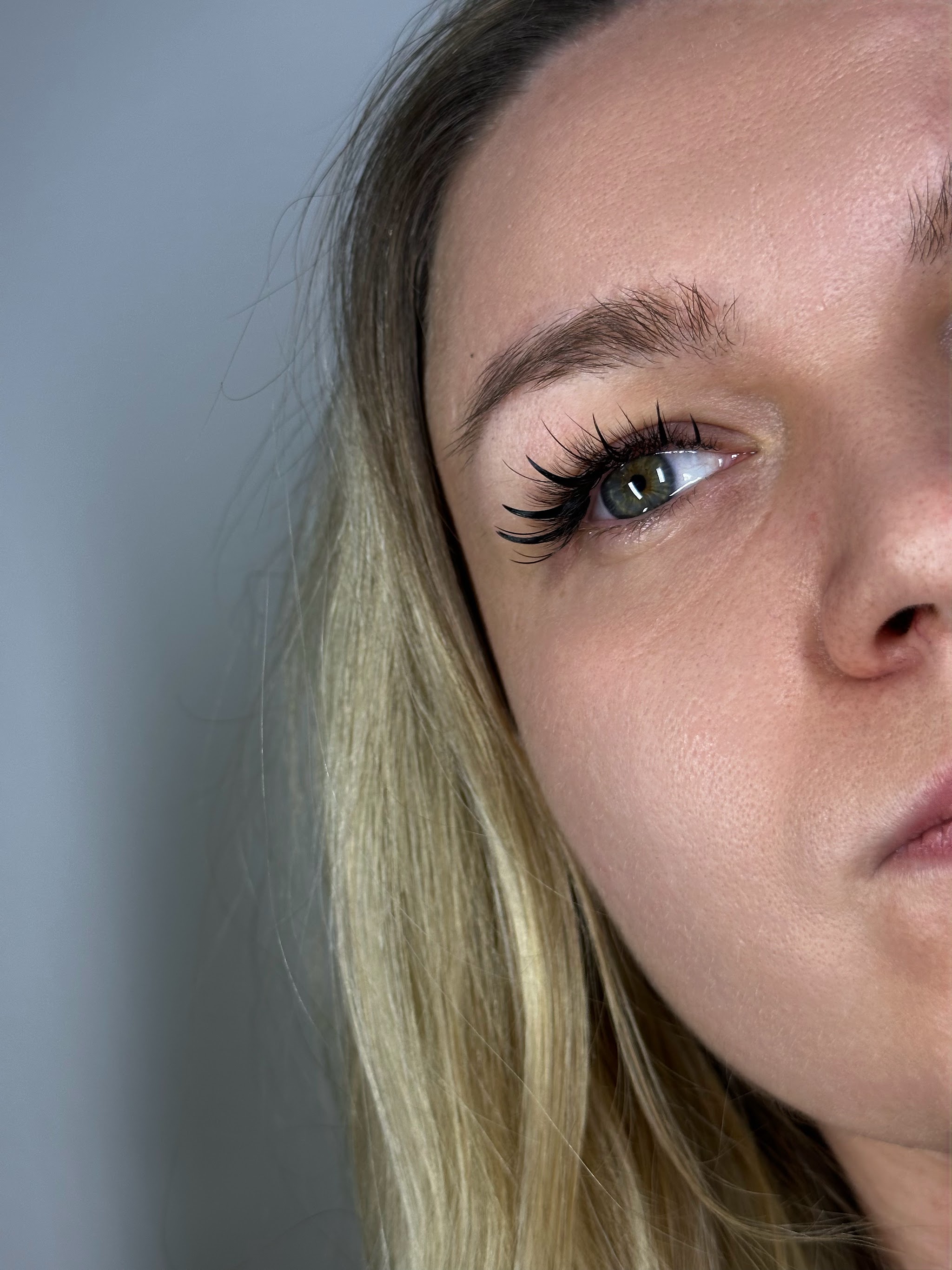 Close-up van natuurlijke wimperextensions bij een blonde klant, van opzij