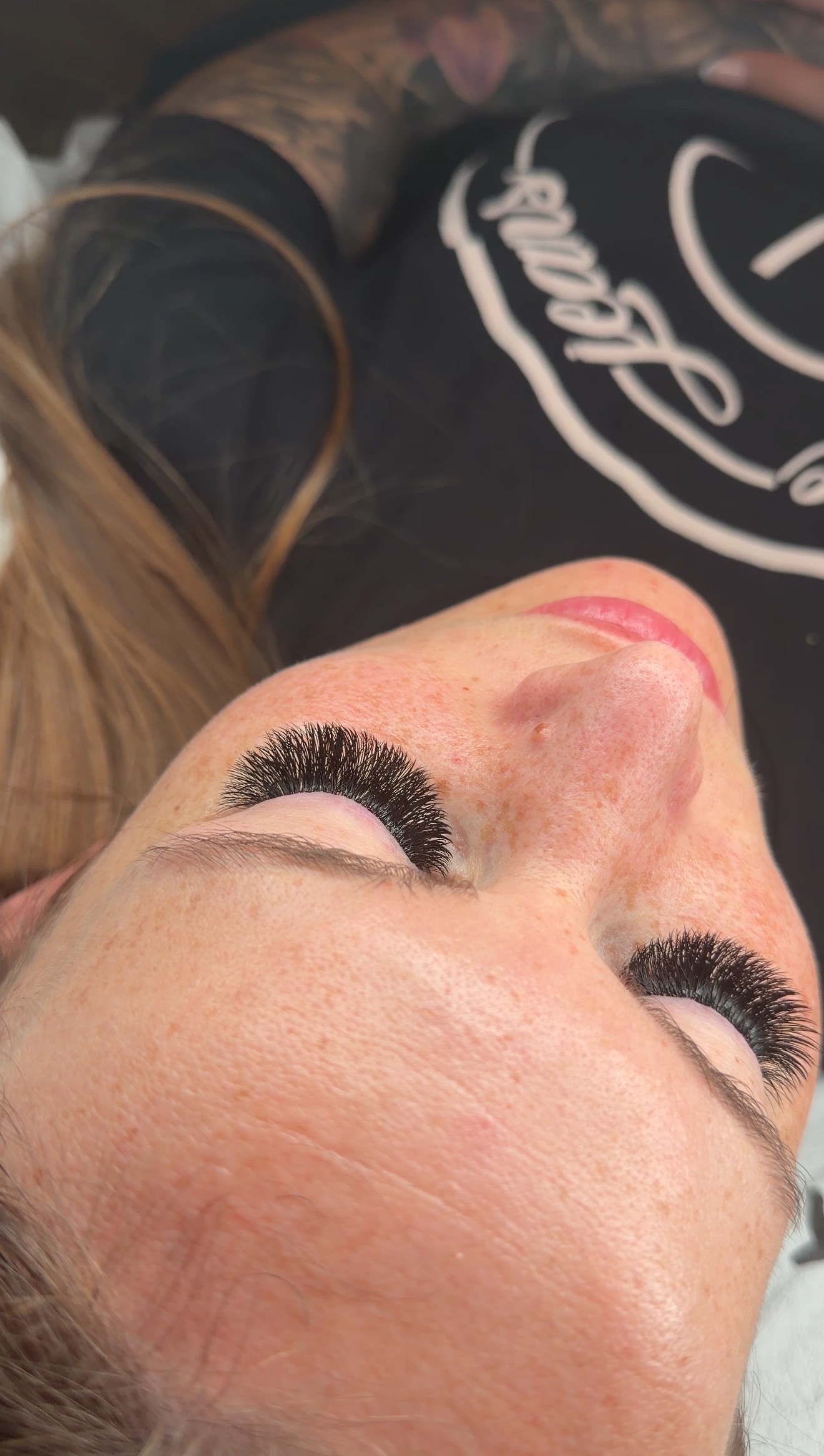 Klant ligt met gesloten ogen op de behandelstoel, met een vol wimperset